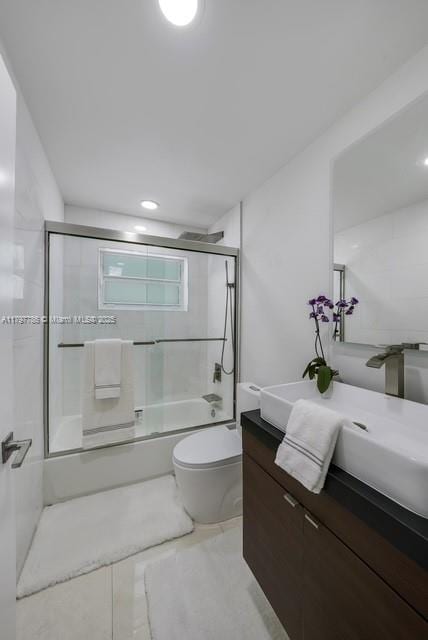 bathroom featuring vanity, combined bath / shower with glass door, toilet, and tile patterned flooring