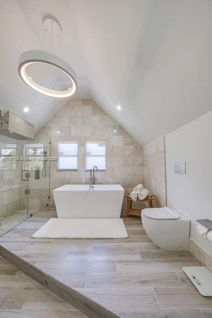 bathroom featuring lofted ceiling, a shower stall, a soaking tub, and toilet