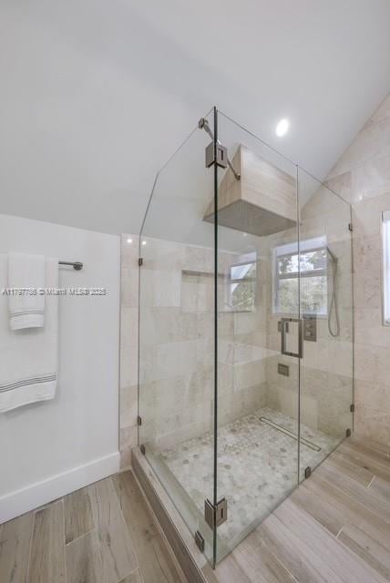 full bath featuring wood finished floors, a stall shower, and vaulted ceiling
