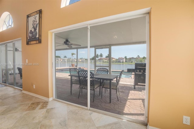 dining area featuring ceiling fan, baseboards, and a water view