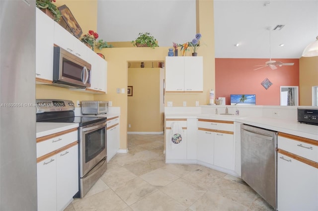 kitchen featuring appliances with stainless steel finishes, light countertops, white cabinets, ceiling fan, and a sink