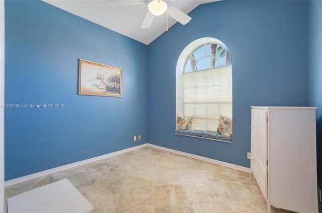 spare room with a ceiling fan, lofted ceiling, and baseboards