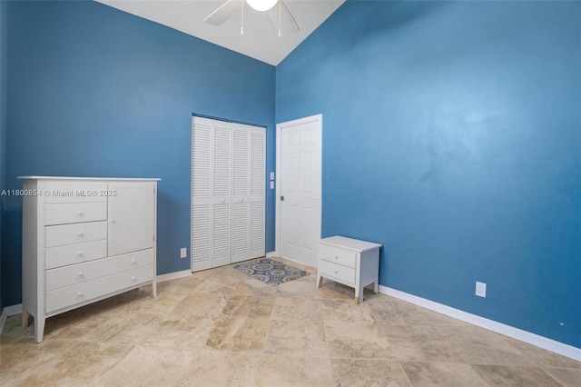unfurnished bedroom with high vaulted ceiling, baseboards, ceiling fan, and a closet