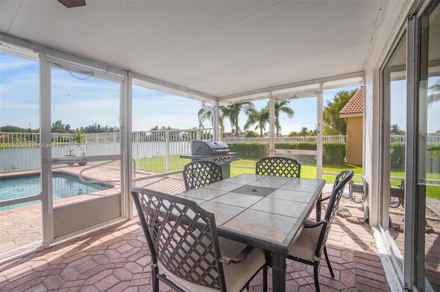 sunroom featuring a water view, plenty of natural light, and outdoor dining space