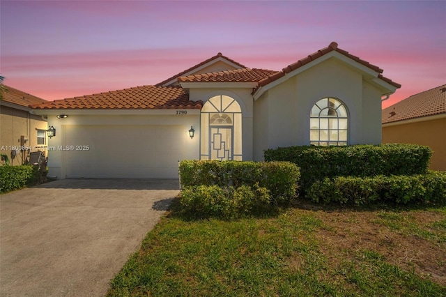 mediterranean / spanish-style house featuring a garage, concrete driveway, stucco siding, and a tile roof