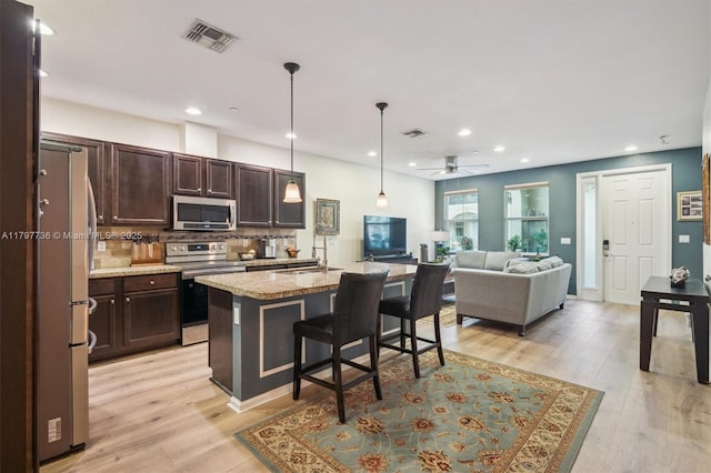 4346 Cascada Cir, Cooper City, FL 33024 - kitchen featuring appliances with stainless steel finishes, dark brown cabinets, a breakfast bar area, open floor plan, and a sink