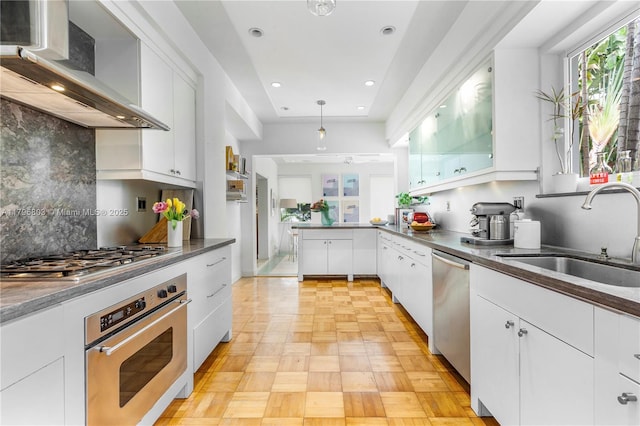 4532 Sheridan Ave, Miami Beach, FL 33140 - kitchen featuring appliances with stainless steel finishes, wall chimney range hood, a sink, white cabinetry, and recessed lighting