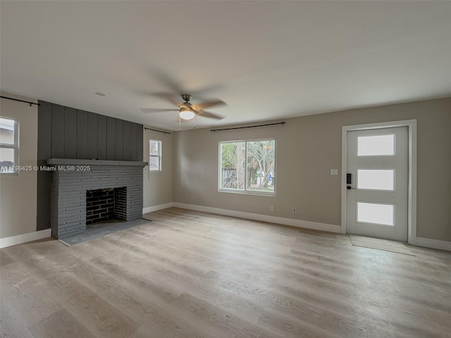 unfurnished living room featuring a ceiling fan, a fireplace, light wood-style flooring, and baseboards