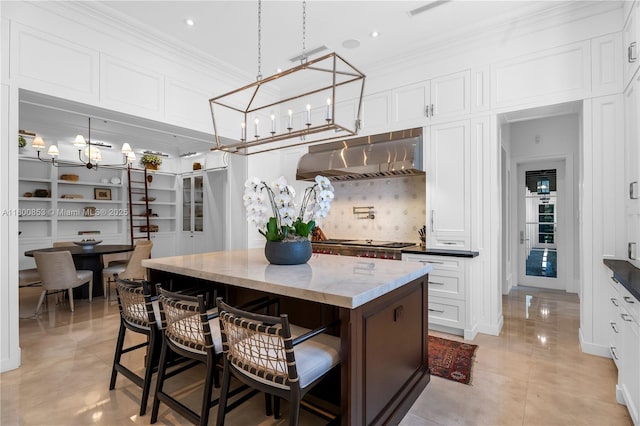 kitchen featuring under cabinet range hood, white cabinetry, a breakfast bar area, ornamental molding, and a kitchen island