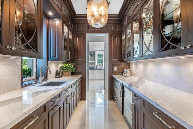 kitchen with a sink, dark brown cabinetry, backsplash, plenty of natural light, and ornamental molding