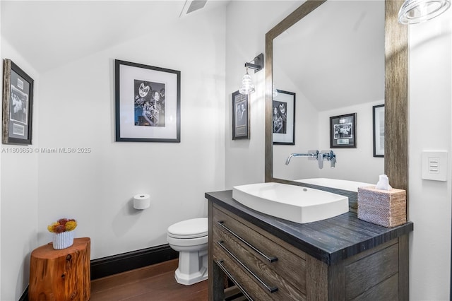 bathroom featuring lofted ceiling, wood finished floors, toilet, and vanity