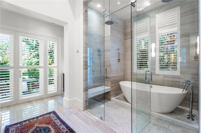 bathroom with a shower stall, a soaking tub, plenty of natural light, and tile patterned flooring