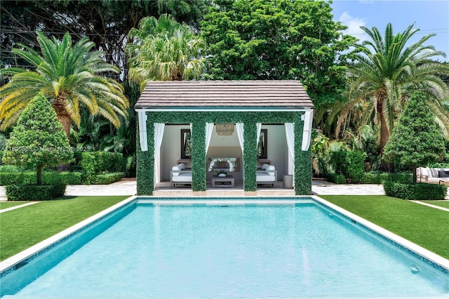 outdoor pool featuring a storage structure, an outbuilding, an outdoor living space, and a lawn