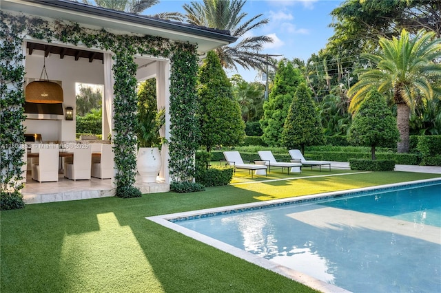 outdoor pool with a patio, a lawn, and a bar