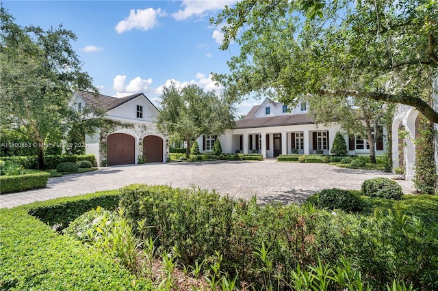 view of front facade featuring decorative driveway, an attached garage, and stucco siding