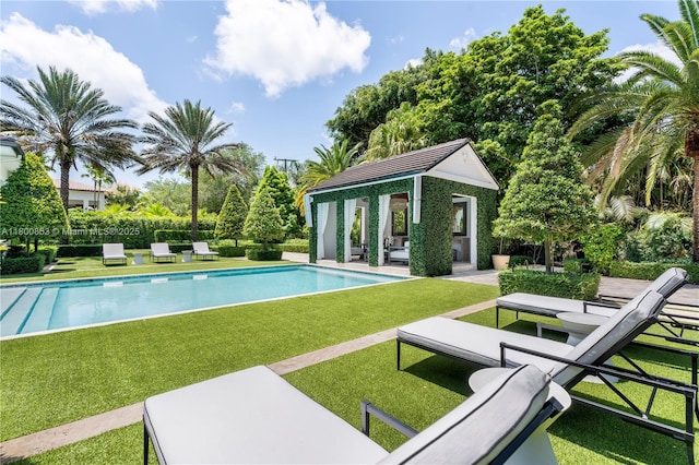 swimming pool featuring an exterior structure, an outdoor structure, a lawn, and a patio
