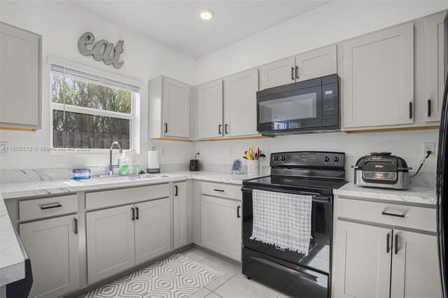 550 NE 4th Ave, Florida City, FL 33034 - kitchen featuring black appliances, a peninsula, gray cabinetry, a sink, and a kitchen bar