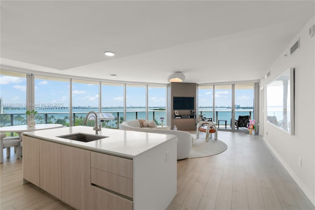 488 NE 18th St Unit 715, Miami, FL 33132 - kitchen featuring modern cabinets, light brown cabinets, a sink, open floor plan, and light wood finished floors