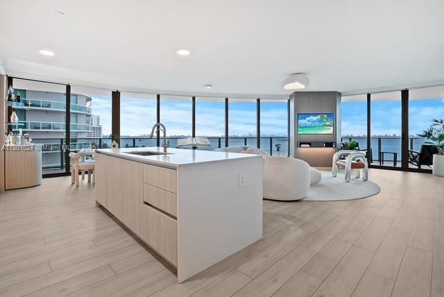 488 NE 18th St Unit 715, Miami, FL 33132 - kitchen with modern cabinets, expansive windows, a sink, light wood-style flooring, and an island with sink