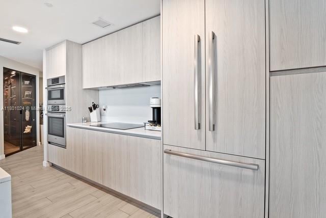 488 NE 18th St Unit 715, Miami, FL 33132 - kitchen featuring paneled fridge, modern cabinets, black electric stovetop, light wood finished floors, and light countertops