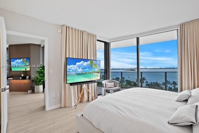 488 NE 18th St Unit 715, Miami, FL 33132 - bedroom with light wood-style floors, baseboards, and a wall of windows