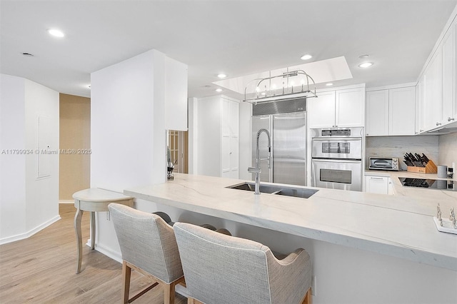 9401 Collins Ave Unit 505, Surfside, FL 33154 - kitchen featuring stainless steel appliances, light wood-type flooring, light stone counters, recessed lighting, and a peninsula
