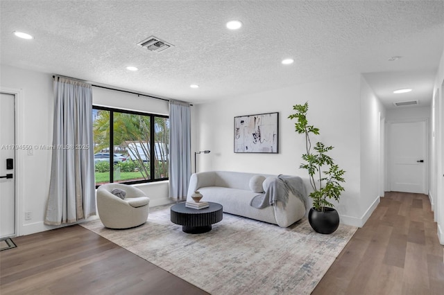 living area with a textured ceiling, wood finished floors, recessed lighting, and baseboards