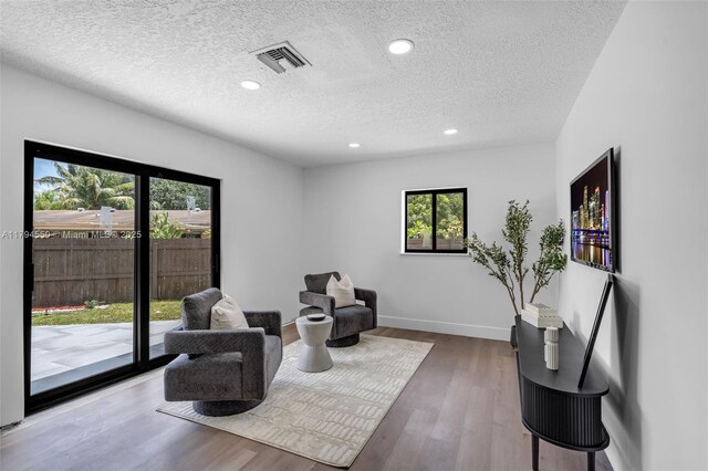 living area featuring a textured ceiling, wood finished floors, recessed lighting, and baseboards