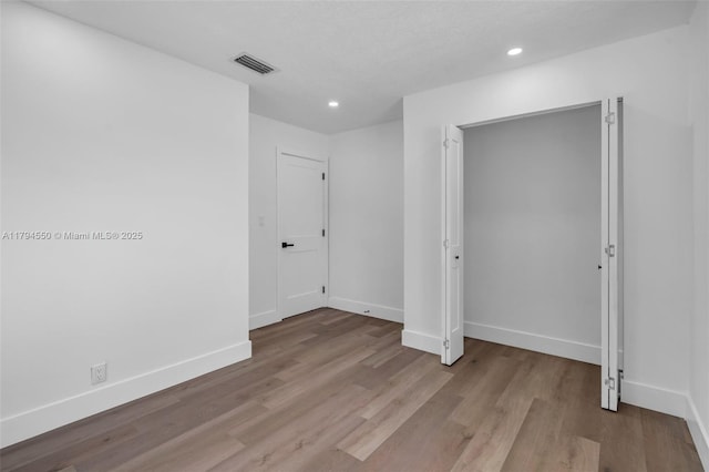 unfurnished bedroom featuring wood finished floors, baseboards, and recessed lighting