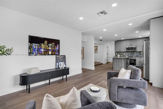 living room with baseboards, recessed lighting, and light wood-type flooring