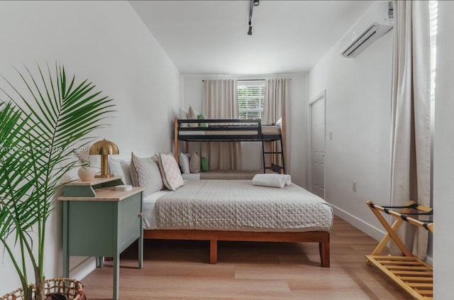 1153 NE 158th St, North Miami Beach, FL 33162 - bedroom with light wood-type flooring, a wall unit AC, rail lighting, and baseboards