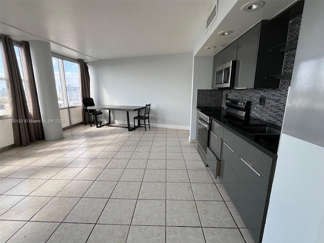 900 Bay Dr Unit 913, Miami Beach, FL 33141 - kitchen featuring stainless steel appliances, dark countertops, tasteful backsplash, baseboards, and light tile patterned floors
