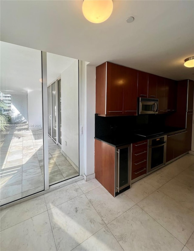 901 Brickell Key Blvd Unit 603, Miami, FL 33131 - kitchen with appliances with stainless steel finishes, beverage cooler, dark countertops, backsplash, and reddish brown cabinets