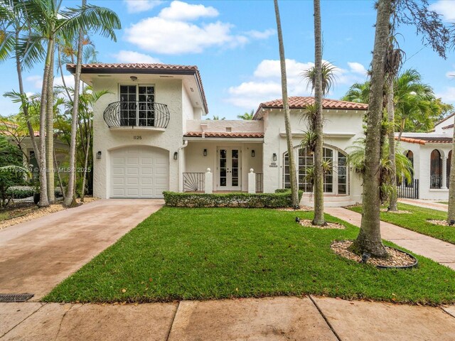 1125 Asturia Ave, Coral Gables, FL 33134 - mediterranean / spanish house with french doors, a tile roof, stucco siding, a garage, and a front lawn
