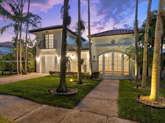 1125 Asturia Ave, Coral Gables, FL 33134 - mediterranean / spanish house with french doors, a balcony, stucco siding, driveway, and a tile roof
