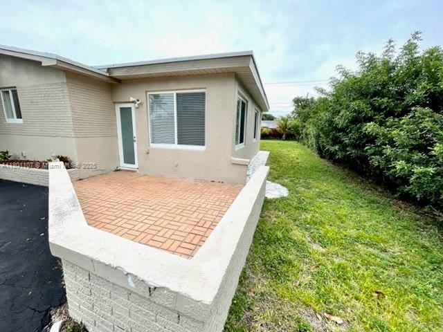 1900 NE 180th St, North Miami Beach, FL 33162 - view of property exterior with a yard, a patio, and stucco siding