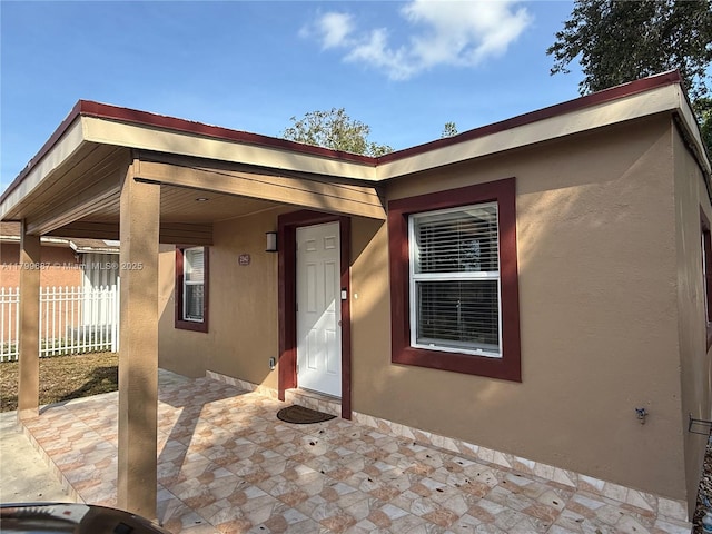 view of front of house with fence, stucco siding, and a patio