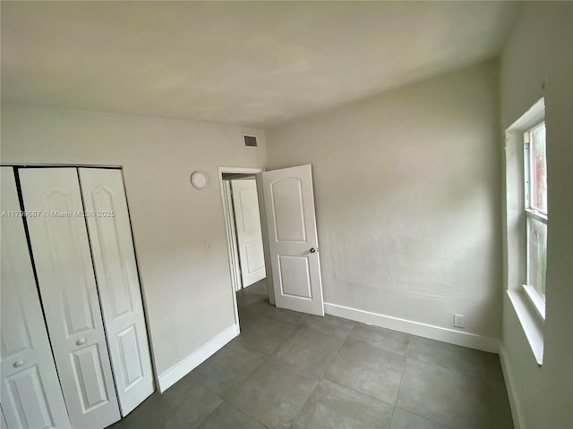 unfurnished bedroom with baseboards, a closet, and tile patterned flooring