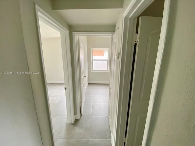 corridor featuring light tile patterned floors and baseboards