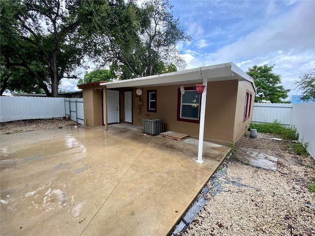 rear view of property featuring central AC unit, stucco siding, a fenced backyard, and a patio