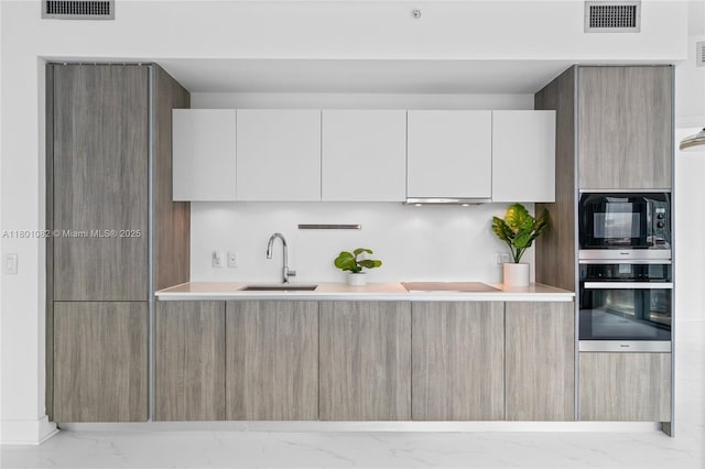 2900 NE 7th Ave Unit 1409, Miami, FL 33137 - kitchen featuring oven, modern cabinets, black microwave, marble finish floors, and cooktop