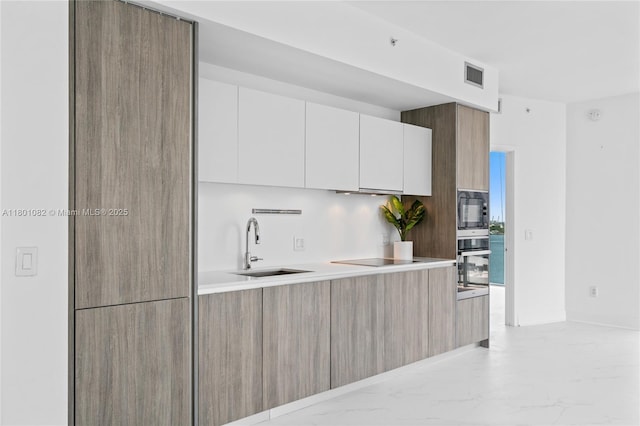 2900 NE 7th Ave Unit 1409, Miami, FL 33137 - kitchen featuring modern cabinets, black appliances, light marble finish flooring, and white cabinetry