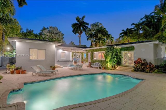 5550 N Bayshore Dr, Miami, FL 33137 - back of house at night featuring a patio, an outdoor pool, entry steps, and stucco siding