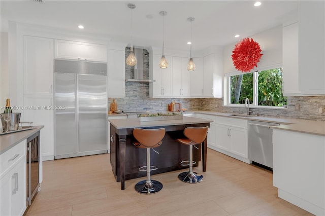 5550 N Bayshore Dr, Miami, FL 33137 - kitchen with appliances with stainless steel finishes, wall chimney range hood, decorative backsplash, white cabinets, and light countertops