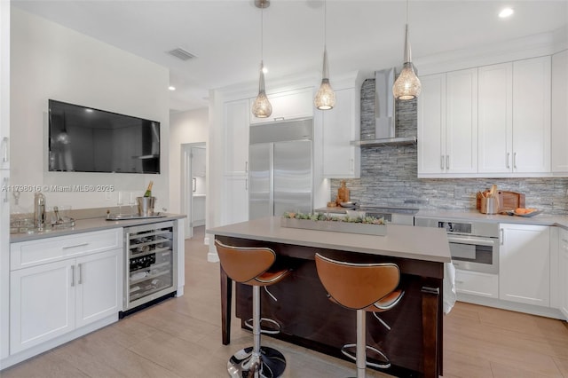 5550 N Bayshore Dr, Miami, FL 33137 - kitchen with appliances with stainless steel finishes, beverage cooler, wall chimney range hood, backsplash, and white cabinetry