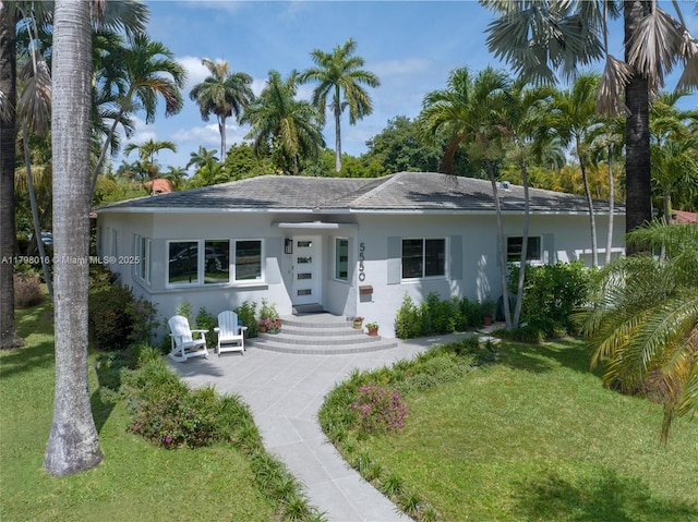 5550 N Bayshore Dr, Miami, FL 33137 - view of front facade with a front lawn, stucco siding, and roof with shingles