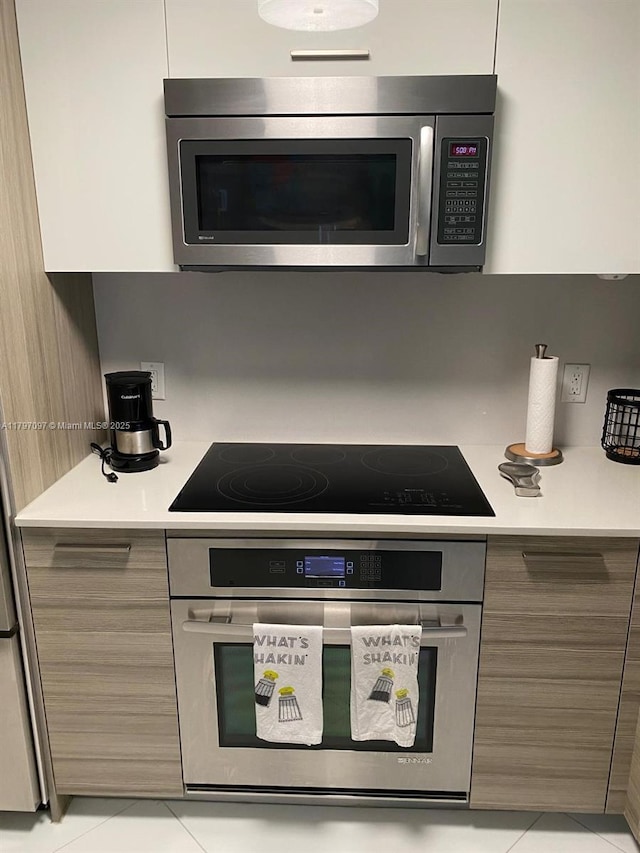 kitchen with appliances with stainless steel finishes, modern cabinets, light countertops, and light tile patterned floors