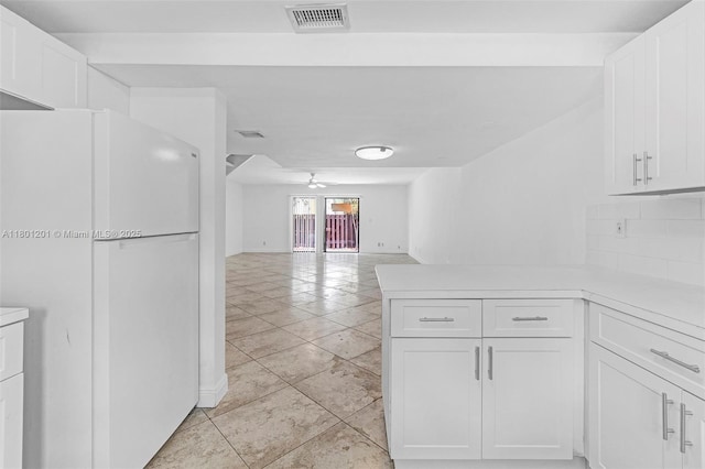 kitchen with freestanding refrigerator, white cabinetry, a peninsula, light countertops, and light tile patterned floors