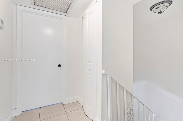 corridor featuring light tile patterned floors and baseboards