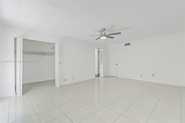 unfurnished bedroom featuring light tile patterned floors, a textured ceiling, ceiling fan, a closet, and baseboards